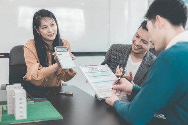 Bir grup Asyalı genç iş adamı emlak projesi için bir ofiste buluşuyorlar. Bir grup zarif, profesyonel giyimli birey küçük bir ev modelini değerlendiriyor..