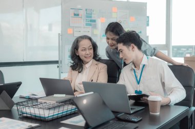 Bir grup iş adamı çalışma masalarında birlikte çalışan ve belgeleri tartışan çalışma arkadaşlarının sonuçlarını gösteren çizelge ve grafikleri tartışıyor..