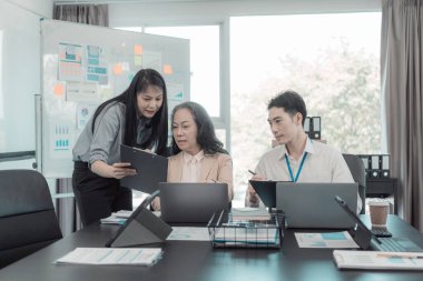 Bir grup iş adamı çalışma masalarında birlikte çalışan ve belgeleri tartışan çalışma arkadaşlarının sonuçlarını gösteren çizelge ve grafikleri tartışıyor..