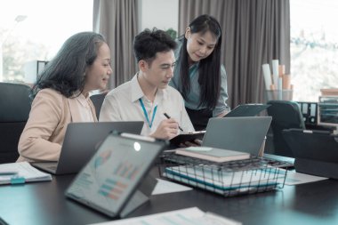 Bir grup iş adamı çalışma masalarında birlikte çalışan ve belgeleri tartışan çalışma arkadaşlarının sonuçlarını gösteren çizelge ve grafikleri tartışıyor..