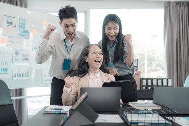 Bir grup başarılı Asyalı iş adamı gülümseyip gülüyor, poz veriyor ve bir şirket ofisindeki konferans salonunda neşe jestleri yapıyor..