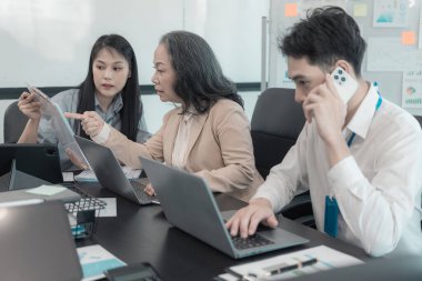 Bir grup iş adamı çalışma masalarında birlikte çalışan ve belgeleri tartışan çalışma arkadaşlarının sonuçlarını gösteren çizelge ve grafikleri tartışıyor..