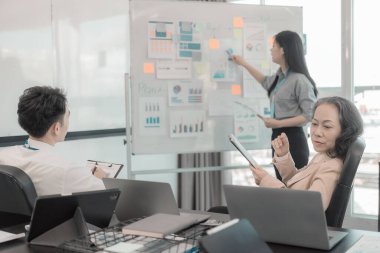 Bir grup iş adamı çalışma masalarında birlikte çalışan ve belgeleri tartışan çalışma arkadaşlarının sonuçlarını gösteren çizelge ve grafikleri tartışıyor..