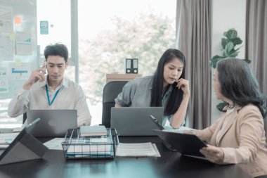 Bir grup iş adamı çalışma masalarında birlikte çalışan ve belgeleri tartışan çalışma arkadaşlarının sonuçlarını gösteren çizelge ve grafikleri tartışıyor..