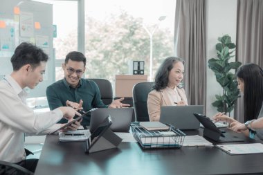 Bir grup iş adamı çalışma masalarında birlikte çalışan ve belgeleri tartışan çalışma arkadaşlarının sonuçlarını gösteren çizelge ve grafikleri tartışıyor..