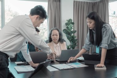 Bir grup iş adamı çalışma masalarında birlikte çalışan ve belgeleri tartışan çalışma arkadaşlarının sonuçlarını gösteren çizelge ve grafikleri tartışıyor..