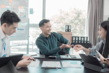 Bir grup iş adamı çalışma masalarında birlikte çalışan ve belgeleri tartışan çalışma arkadaşlarının sonuçlarını gösteren çizelge ve grafikleri tartışıyor..