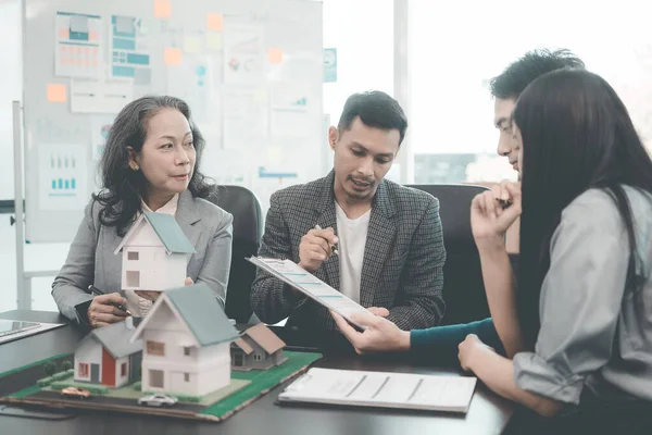 Bir grup Asyalı genç iş adamı emlak projesi için bir ofiste buluşuyorlar. Bir grup zarif, profesyonel giyimli birey küçük bir ev modelini değerlendiriyor..