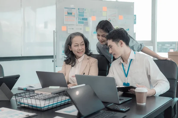 Bir grup iş adamı çalışma masalarında birlikte çalışan ve belgeleri tartışan çalışma arkadaşlarının sonuçlarını gösteren çizelge ve grafikleri tartışıyor..