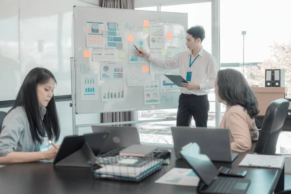 Bir grup iş adamı çalışma masalarında birlikte çalışan ve belgeleri tartışan çalışma arkadaşlarının sonuçlarını gösteren çizelge ve grafikleri tartışıyor..