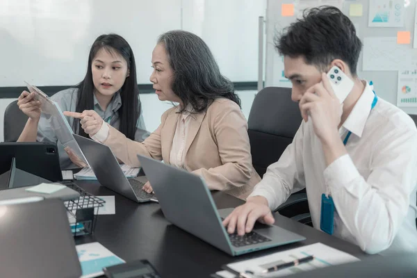 Bir grup iş adamı çalışma masalarında birlikte çalışan ve belgeleri tartışan çalışma arkadaşlarının sonuçlarını gösteren çizelge ve grafikleri tartışıyor..