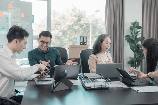 Bir grup iş adamı çalışma masalarında birlikte çalışan ve belgeleri tartışan çalışma arkadaşlarının sonuçlarını gösteren çizelge ve grafikleri tartışıyor..