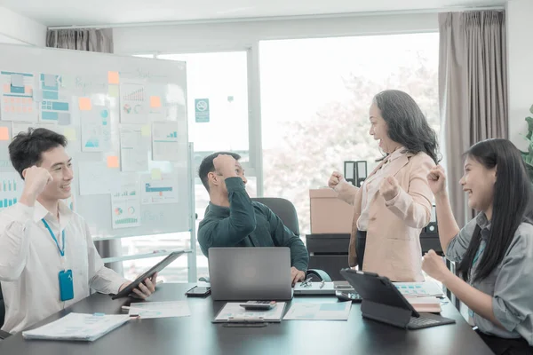 Bir grup başarılı Asyalı iş adamı gülümseyip gülüyor, poz veriyor ve bir şirket ofisindeki konferans salonunda neşe jestleri yapıyor..