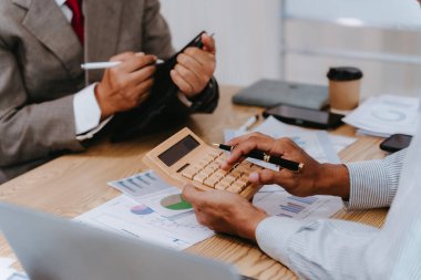 İş adamları takım çalışmasının sonuçlarını, etkin veri analizini ve maliye bakanlığının planlamasının başarısını gösteren çizelge ve grafikleri tartışıyor..