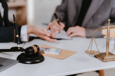 Bir avukat müvekkille mahkeme salonunda bir sözleşme imzalıyor. Bir müşteriyle anlaşma yapıyor. Masada Adalet Tanrıçası 'nın bir heykeli ve bir terazisi var..