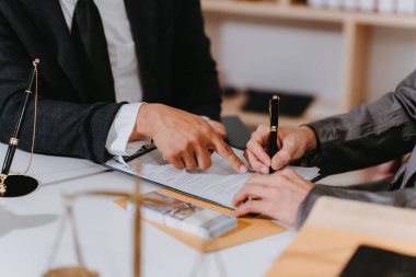 Bir avukat müvekkille mahkeme salonunda bir sözleşme imzalıyor. Bir müşteriyle anlaşma yapıyor. Masada Adalet Tanrıçası 'nın bir heykeli ve bir terazisi var..