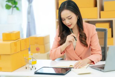 Asian woman using laptop with box, successful cheerful for online marketing packaging and delivery concept SME, small business entrepreneur, SME freelancer.
