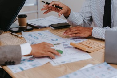 Group of business people discussing charts and graphs showing results of teamwork using laptops. Strategic planning and brainstorming. Colleagues.