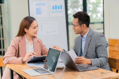 Asyalı işadamı ve kadın, iş stratejisini tartışmak ve veri, grafik veya grafikleri analiz etmek için belgeler ve tablet dizüstü bilgisayarla birlikte çalışıyor.