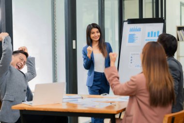 Bir grup Asyalı genç işadamı ve kadın, ofiste başarılı bir toplantı veya sunum sonrasında birbirlerini alkışlıyorlar..