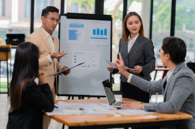 Bir grup iş adamı ofis konferans odasında iş planını tartışıyor. Proje planlaması, yaratıcı beyin fırtınası, fikirleri tartışmak, belgeler kullanmak, dijital cihazlar.