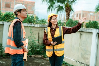 Mühendisler ve mimarlar arazi planlarıyla çalışır, kavramları geliştirirler. Güzel, genç bir kadın, bir ortak, yeni evinin inşaatı projesinden memnun..