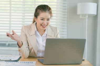 Asyalı bir iş kadını, bir iş ve teknoloji konsepti şirketinin muhasebe ve vergi konularıyla ilgilenerek muhasebe analizi raporları hazırlıyor..