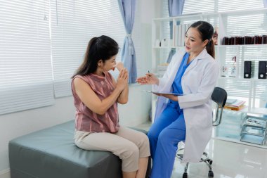 Asyalı bir kadın fizyoterapist yaşlı bir hastaya kas rehabilitasyonuna yardım etmek için fizik tedavi uyguluyor..