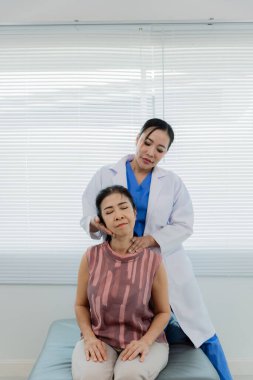 Asyalı bir kadın fizyoterapist yaşlı bir hastaya kas rehabilitasyonuna yardım etmek için fizik tedavi uyguluyor..