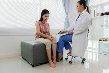 Asyalı bir kadın fizyoterapist yaşlı bir hastaya kas rehabilitasyonuna yardım etmek için fizik tedavi uyguluyor..