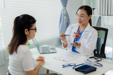 Bir doktor ve bir hasta bir masada oturmuş miyopluk, sağlık ve ilaç kavramlarının tedavisini tartışıyorlar..