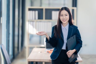 Başarılı bir Asyalı iş kadını ofiste kameraya gülümsüyor..