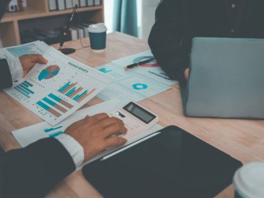 İş dünyası ekibi başarılı takım çalışmalarının, finansal konseptlerin ve yakın çekim çekimlerinin sonuçlarını gösteren çizelge ve grafikleri tartışıyor..