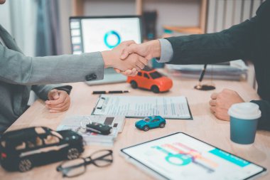 İş adamları araba satışını tamamladıktan sonra el sıkışıyor. Araba satın alma anlaşmasına göre iki kişi arabanın anahtarlarını koydukları masada el sıkışıyor..