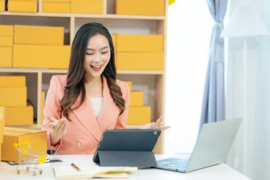 Kendi iş yeri olan Asyalı bir kadın ev ofis formatında çalışır, evden bir dizüstü bilgisayar kullanarak online satışlara odaklanır ve küçük bir girişim yürütür..