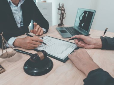 Avukat, yasal danışma toplantısında müvekkilini temsil eden ve yasal belgelere yardımcı olan yasal bir belgeye imza noktalarını işaret ediyor..