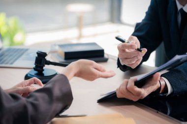 Avukat, yasal danışma toplantısında müvekkilini temsil eden ve yasal belgelere yardımcı olan yasal bir belgeye imza noktalarını işaret ediyor..