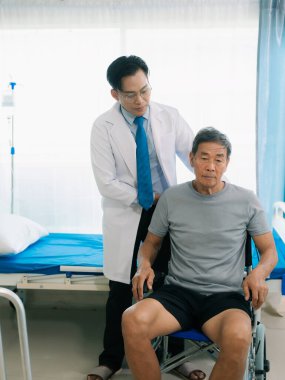 Asyalı bir erkek doktor ve hasta koğuşunda tekerlekli sandalyedeki yaşlı bir hasta. Orta yaşlı bir adam için hastane koğuşunda sağlığını korumak için fizik tedavi..