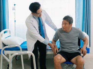 Asyalı bir erkek doktor ve hasta koğuşunda tekerlekli sandalyedeki yaşlı bir hasta. Orta yaşlı bir adam için hastane koğuşunda sağlığını korumak için fizik tedavi..
