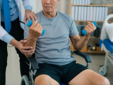 Asyalı bir erkek doktor, terapi ve dayanıklılık eğitimi için yaşlı bir adama tekerlekli sandalyedeki bir adama halterli rehabilitasyon egzersizleri önerdi..
