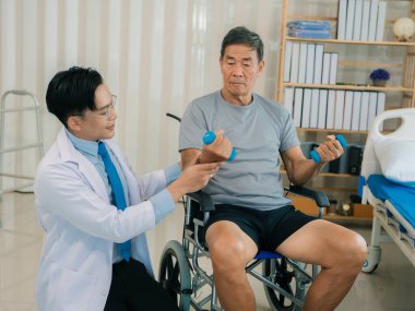 Asyalı bir erkek doktor, terapi ve dayanıklılık eğitimi için yaşlı bir adama tekerlekli sandalyedeki bir adama halterli rehabilitasyon egzersizleri önerdi..