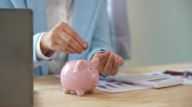 Tasarruf ve muhasebe kavramı: bir iş kadını gelecekte tasarruf hesaplamak için bir hesap makinesi kullanarak bir bardağa para koyuyor..