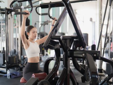 Güzel bir Asyalı kadın spor salonunda çalışıyor. Sağlıklı bir yaşam tarzı için gücünü ve fiziksel uygunluğunu gösteriyor..