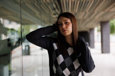 Barcelona 'da şehir meydanında tek başına poz veren genç ve güzel bir kadın. Günlük moda giyinmiş ve gün ışığında kameraya bakıyor..