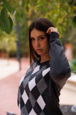 Güzel genç bir kadın, Barcelona Kafe 'nin yanında tek başına duruyor, günlük kıyafetleriyle, kameraya özgüvenle bakıyor, modern şehir yaşamını tasvir ediyor..