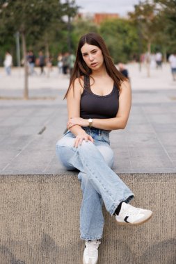 Güzel genç bir kadın Barcelona caddesinde tek başına yürüyor, günlük kıyafetleriyle, kameraya bakıyor, doğal bir şekilde gülümsüyor, keyifli şehir yaşam tarzını görüntülüyor..