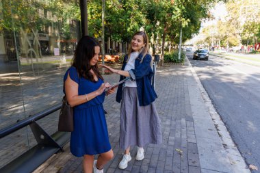 İki gülümseyen kadının harita okuduğu bir şehir manzarası. Bir sonraki durak neresiyse oraya karar veriyorlar..