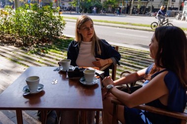 Sıcak gülümsemeler ve sohbet dostluğu ve merakı yansıtır..