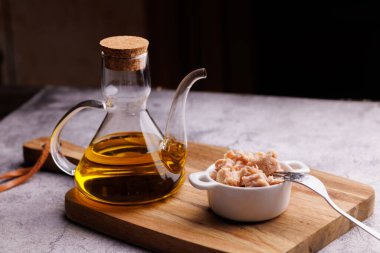 Doğal bir mutfak kompozisyonu için ahşap bir tahtaya konmuş yağlı ton balığı konservesi..
