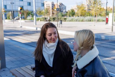 İki arkadaş tramvay peronunda oturup konuşuyorlar ve yolculuklarının tadını çıkarıyorlar.